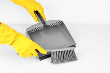 Female hands in rubber gloves with dustpan and brush on white background