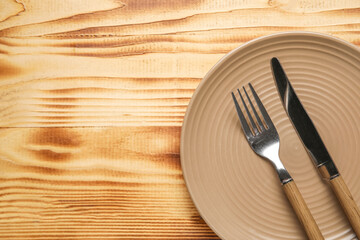 Brown plate with cutlery on wooden background