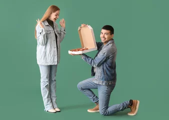 Foto op Aluminium Happy young couple with fresh pizza on green background. Creative marriage proposal © Pixel-Shot