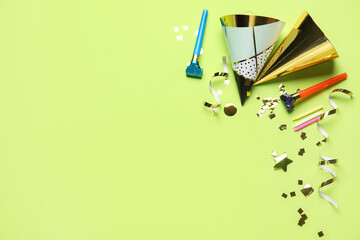 Party hats, confetti, straws and whistles on green background