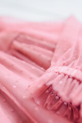 Pink soft tulle polka dot or tulle with flies, texture background. Long sleeve and lined tulle dress for girl, fabric folds waves. Defocused photo.