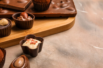 Board with chocolate bars and candies on grunge background, closeup