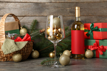 Glass with golden Christmas balls on wooden table, closeup