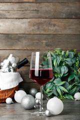 Glass of wine with white Christmas balls on wooden table, closeup