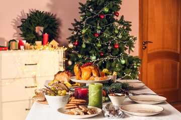Tasty dishes and burning candles for Christmas dinner on table at home
