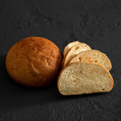 Round loaf of homemade rye bread with cut slices. Traditional family pastry. Fresh bread with crispy crust. Black background. Soft focus. Close-up. Copy space