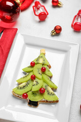 Plate with tasty Christmas tree pancake with fruits on light background, closeup