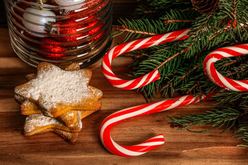 Tasty candy canes, cookies and fir branches on wooden table, closeup