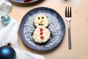 Plate with snowman made of pancakes, whipped cream and Christmas decor on beige table, closeup