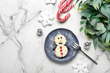 Plate with snowman made of pancakes, whipped cream and Christmas decor on table