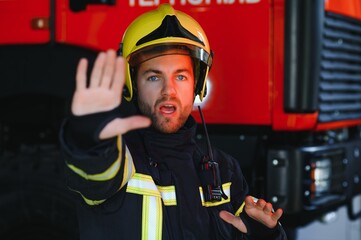 Fototapeta premium Fireman (firefighter) in action standing near a firetruck. Emergency safety. Protection, rescue from danger.
