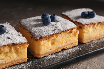 Pieces of cheese pie with blueberries on dark grunge table