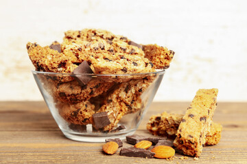 Bowl with tasty biscotti cookies and chocolate on wooden table