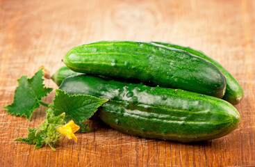 fresh cucumbers with green leaves on wooden background