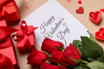 Card with text HAPPY VALENTINE'S DAY, roses and gifts on beige background, closeup