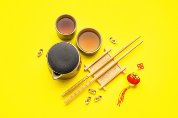 Fototapeta na wymiar Teapot with cups, chopsticks and Chinese symbols on yellow background. New Year celebration