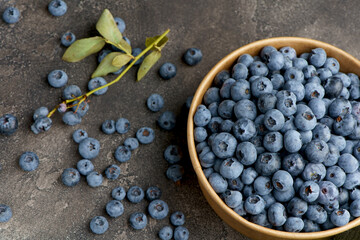 Fresh blueberries with water drops in a wooden bowl. View from above. The concept of healthy and diet food