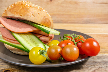 Food background with sandwich with Bologna Sausage and fresh cucumber, cherry tomatoes on ceramic plate.  © Iryna
