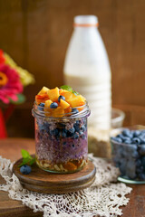 Healthy blueberries and raspberries parfait in mason jars, scene on dark rustic background
