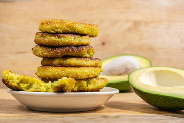 Avocado Corn Fritters or Latkes on wooden background.