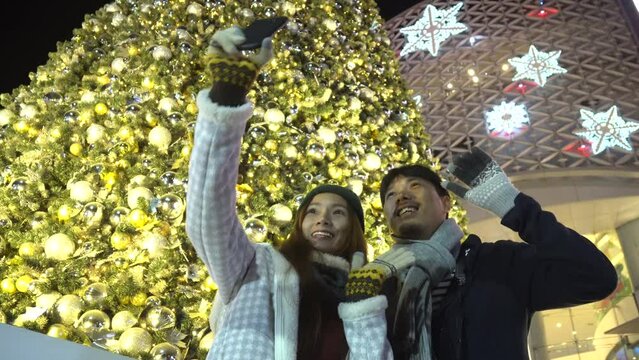 couple holding smartphone selfie Photo celebration at countdown new year in front of church