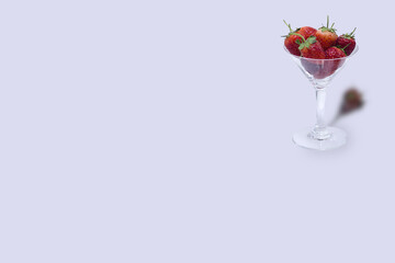 Isolated image of fresh strawberries in glass of champagne on light purple background.
