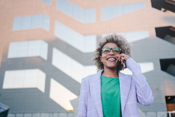 Confident cool African American professional business woman talking on the phone in a modern city