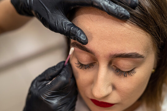Close-up of an eyebrow designer correcting and touching up eyebrows.