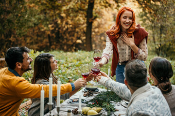 Woman giving a speech to friends at an outdoor party. Young people celebrate a special occasion in a garden restaurant.