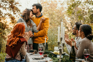 Excited young couple announcing their engagement during a gathering with their friends on an autumn...