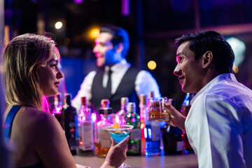Beautiful young couple having fun, drinking alcohol cocktail in a bar.