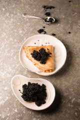 ruddy pancakes with black caviar on a plate