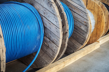 New blue power cable is wound on wooden coil. Background. Cable for laying underground..