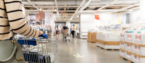 Woman with shopping cart at store, for furniture in warehouse. Many big metal shopping carts for the interior furniture on a parking lot for the customer © jittawit21