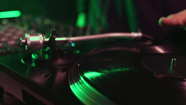 Dj turntable playing vinyl record with music on a party in night club. Professional disc jockey audio equipment filmed in close up