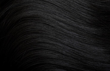 Brunette or black hair. Female long dark hair in black. Beautifully laid curls. Closeup texture in a dark key. Hairdressing, hair care and coloring. Shading gray hair. Background with copy space.