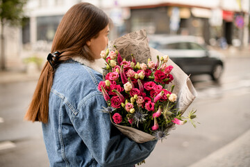 rear view of handsome brunette woman with flower bouquet at street
