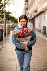 Fototapeta premium handsome brunette woman with flower bouquet at street