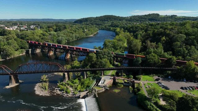 Railroad train crosses bridge over Delaware River in Easton Pennsylvania. Border with New Jersey. Aerial view on sunny day.