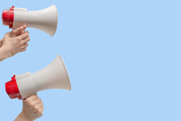 Megaphone in woman hands on a blue background.