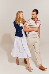 Young and beautiful man and woman in vintage style fashion clothes walking isolated over light background. 60s, 70s american culture concept