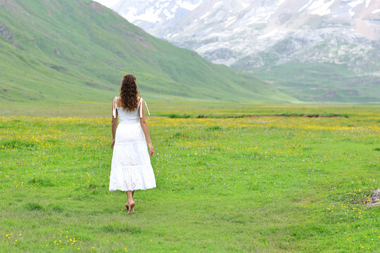Back view of a woman in white dress walking in the mountain