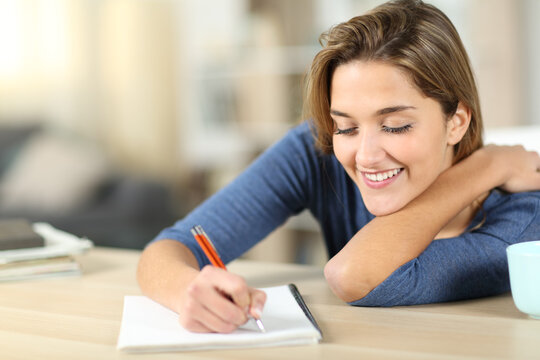 Happy woman taking notes at home