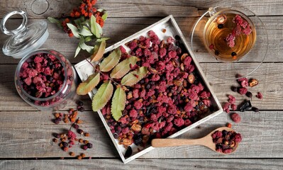 Wooden vintage background with a cup of fruit tea with dried berries of hawthorn, sea buckthorn,...