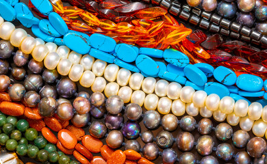 Beads and necklaces made of colored semi precious stones. Background from a variety of beautiful...