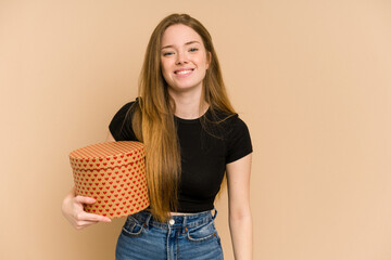 Young redhead woman holding a heart pattern gift for valentines day cut out isolated happy, smiling and cheerful.