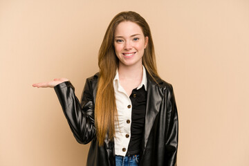 Young redhead woman cut out isolated showing a copy space on a palm and holding another hand on...