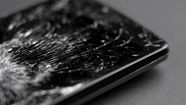 Black smashed crushed mobile phone with broken cracked display. Macro. Rotation