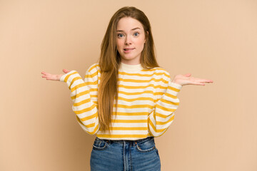 Young redhead woman cut out isolated confused and doubtful shrugging shoulders to hold a copy space.