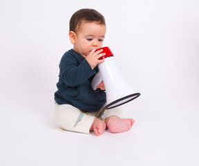 Cute adorable baby boy sitting on white studio background holding a speaker horn sending message....